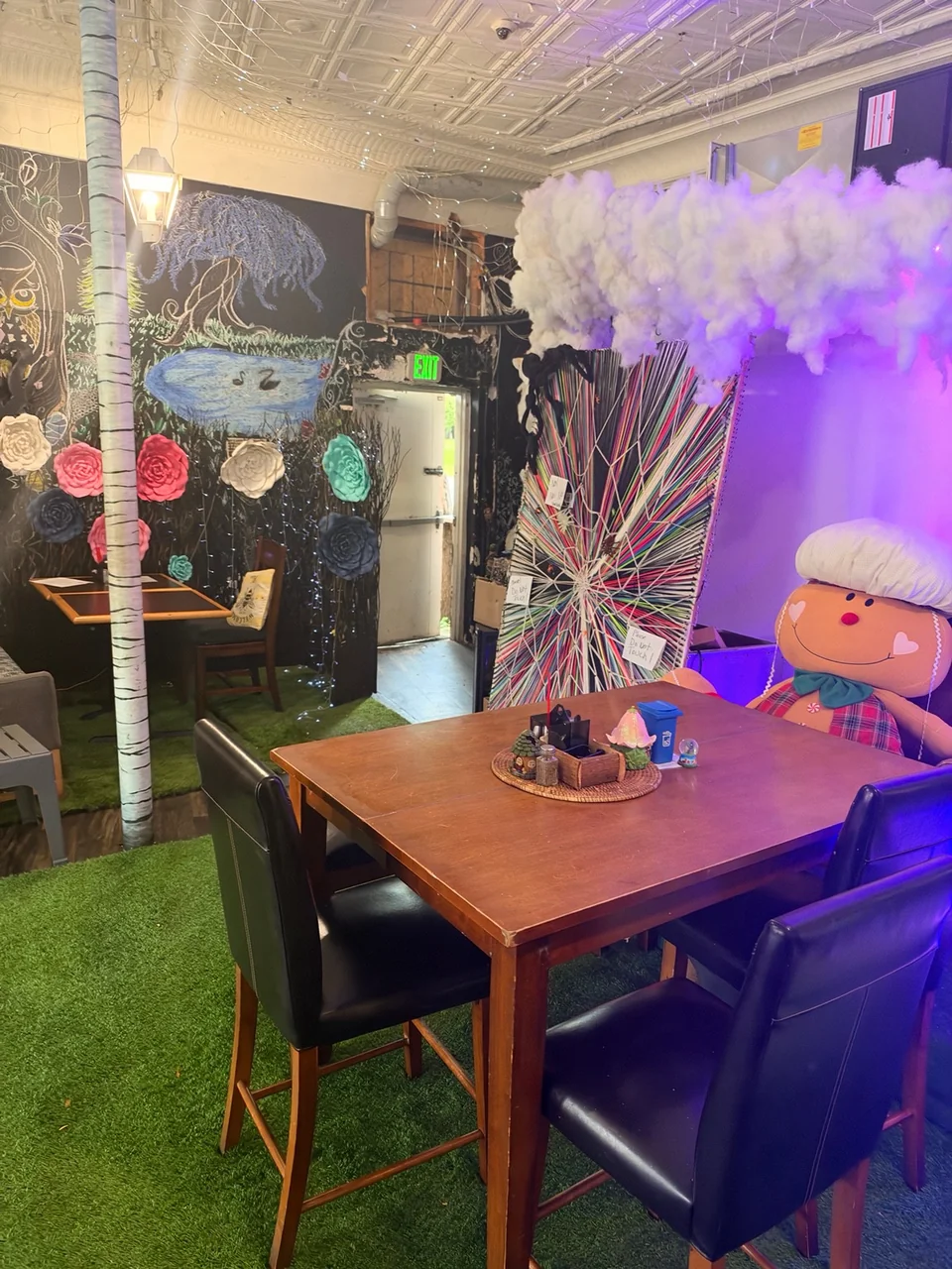 Colorful artwork, hanging clouds and a table inside A Walk in the Park Cafe